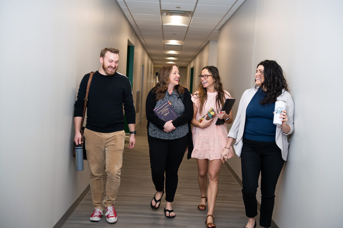 四名学生微笑着走在杰克逊维尔大学大楼的走廊上。万博matext官网网站