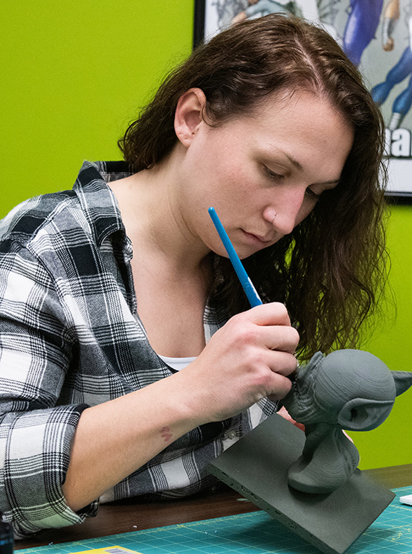 一名学生正在检查3D打印的海豚。