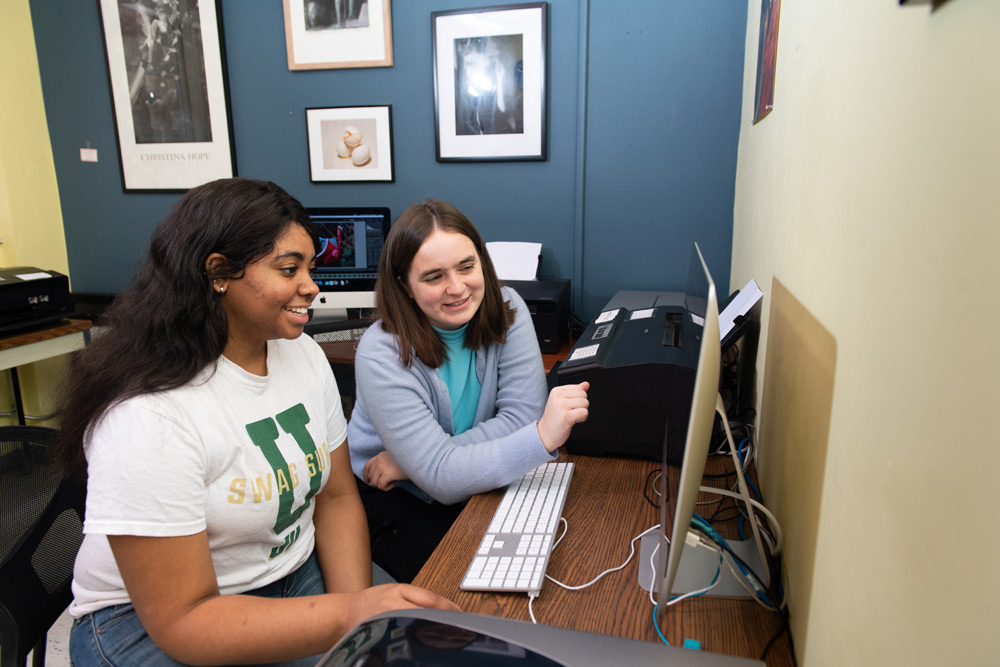 两名学生在数字实验室的iMac上用Lightroom查看照片