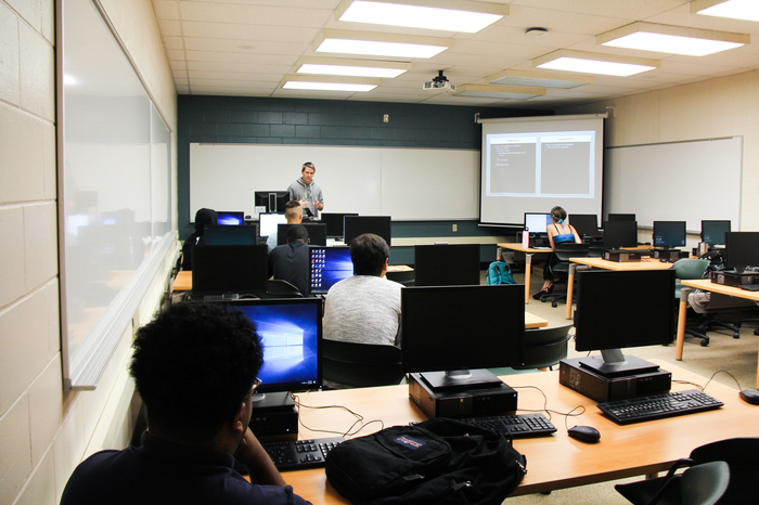 学生在计算机课上听教授讲课。
