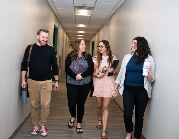 四名学生笑着走在戴维斯商业与技术学院大楼的走廊上。