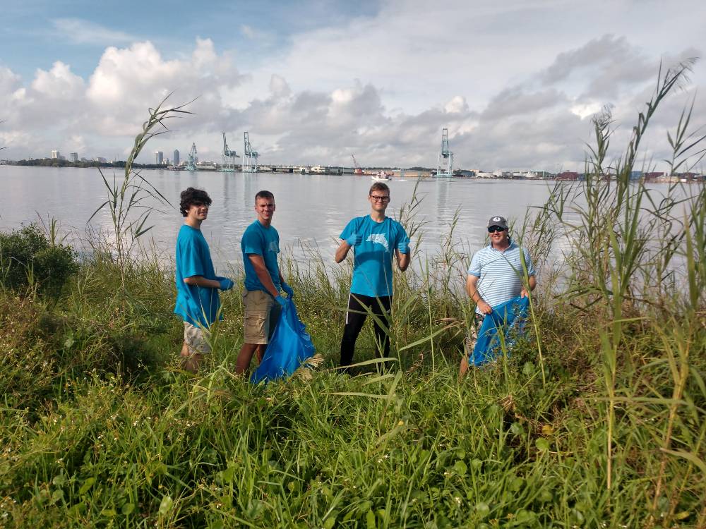 四位男性荣誉志愿者在清理沼泽。