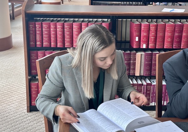 一名女学生在法院图书馆的桌子上阅读教科书。