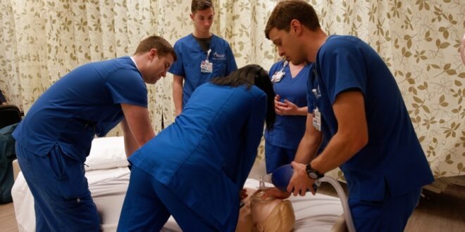 一群医疗保健专业的学生在一个模型病人身上进行呼吸护理。